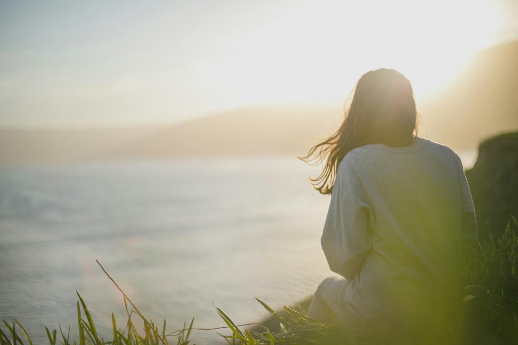 woman sitting on a cliff overlooking the water