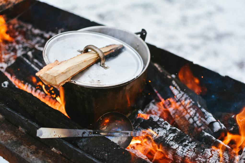 a pot with a lid sitting over a campfire