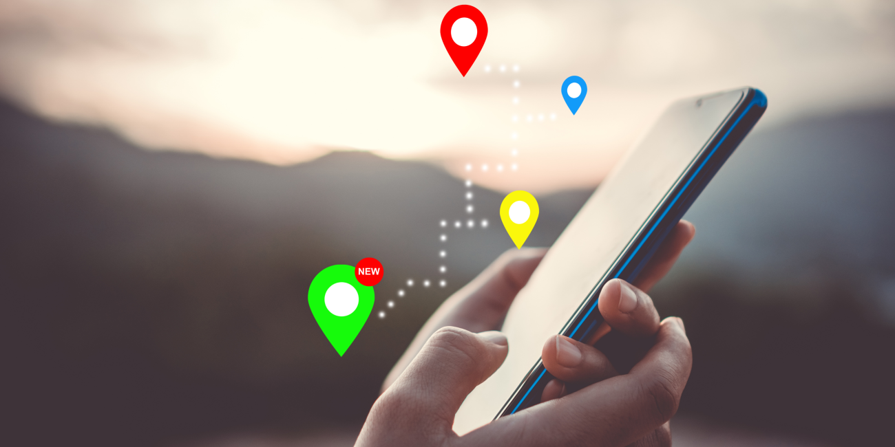 hands holding a phone with gps symbols surrounding it 