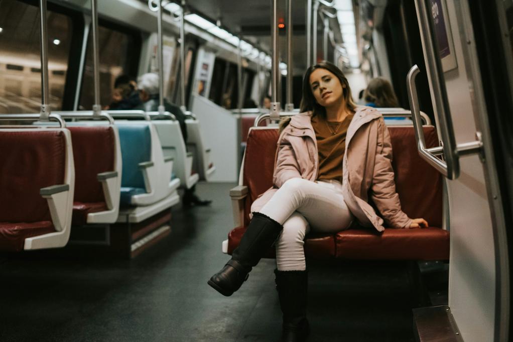 woman sitting on a subway train by herself looking at the camera