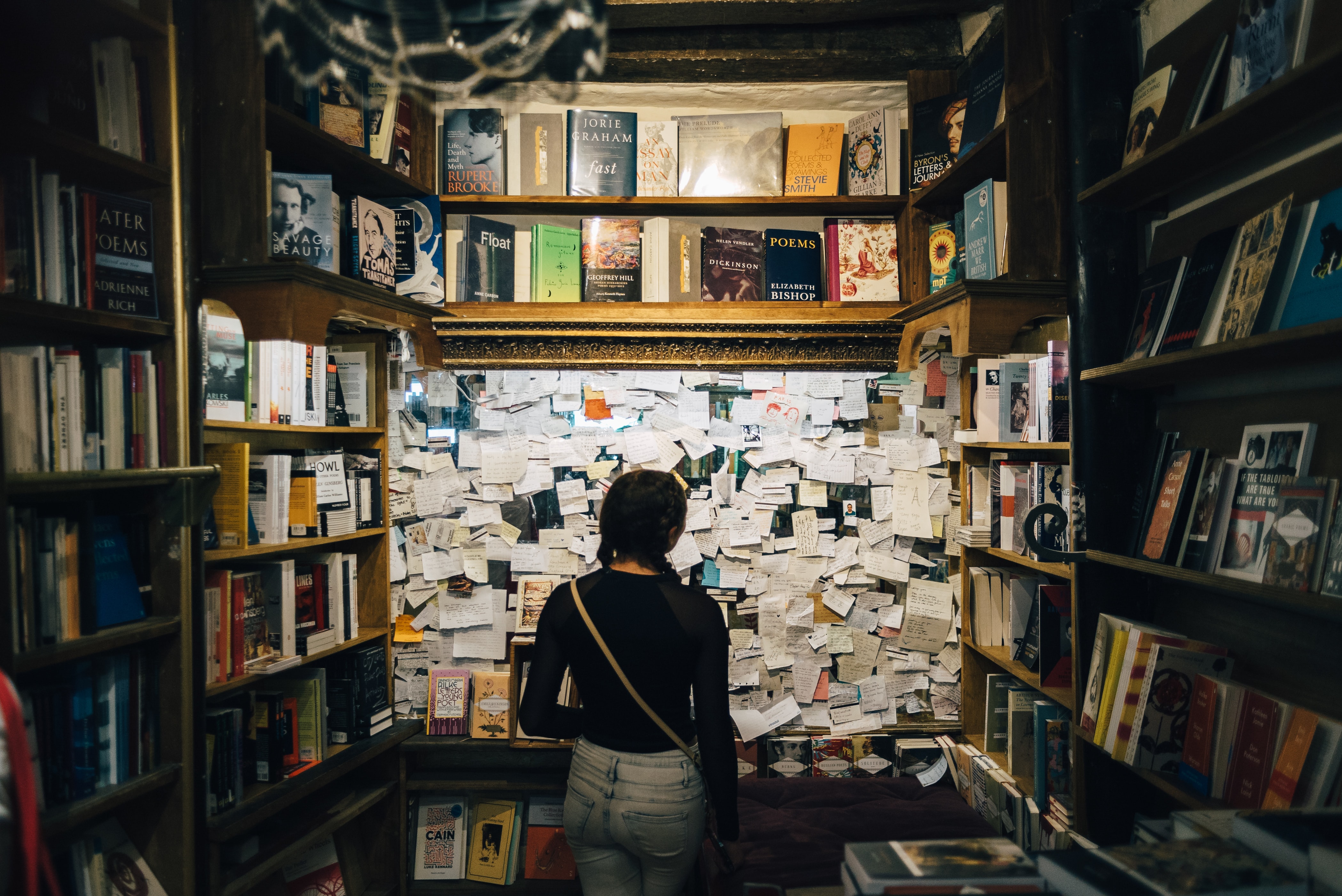 woman standing in a library looking at a board full of pieces of paper