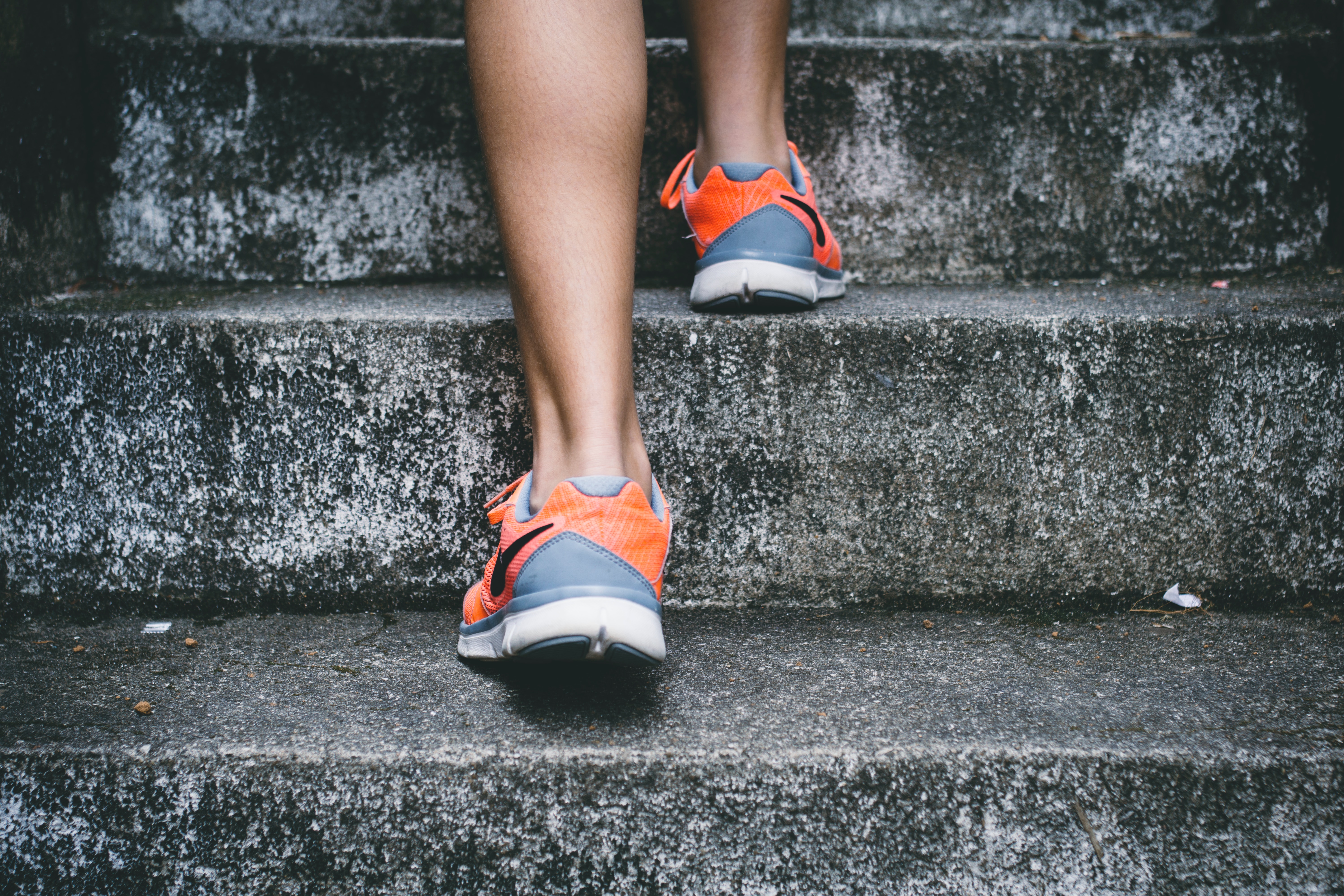 person wearing orange and gray sneakers walking up gray steps