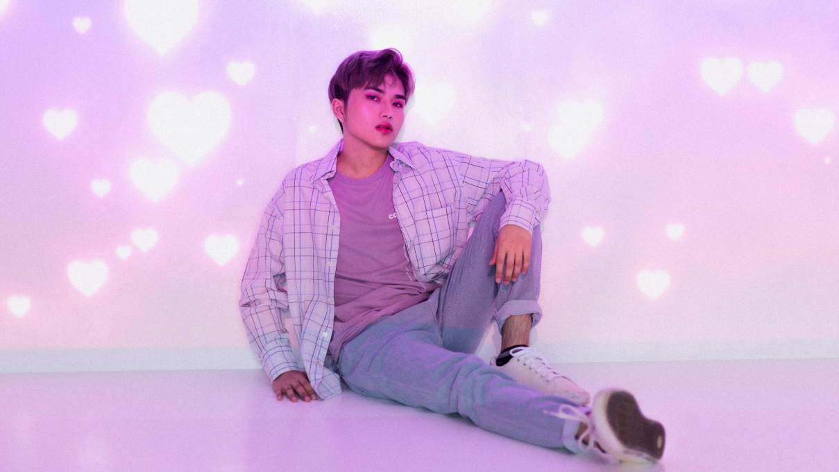 A photo of a k-pop inspired man sitting up against a wall