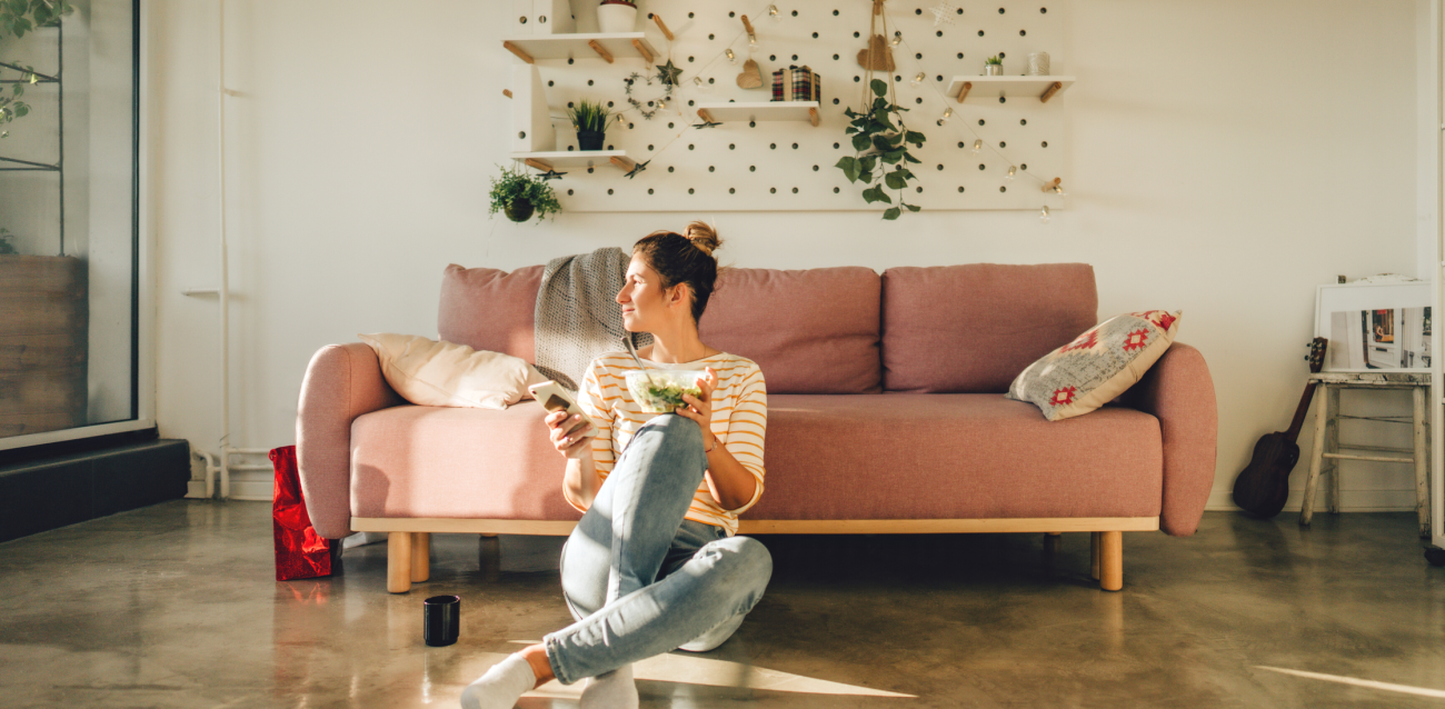 Woman sitting alone in her living room eating a salad