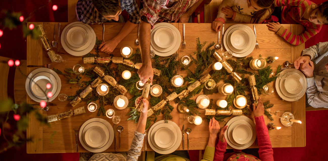family sitting around a christmas dinner table opening christmas crackers