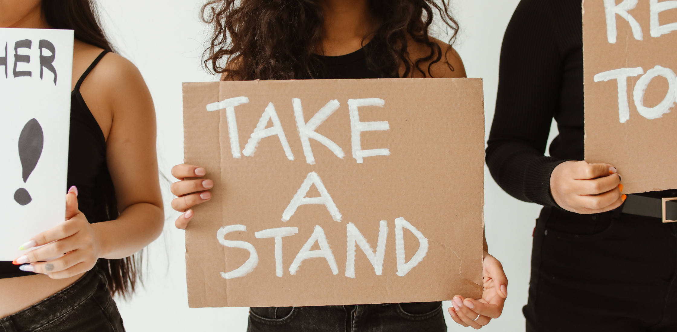 a woman holding a cardboard sign that reads "take a stand"